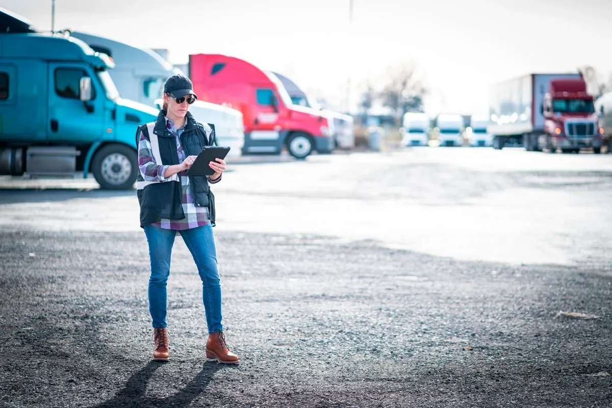 Truck dispatcher using a tablet in a commercial truck yard, managing fleet operations, routing, and compliance tasks.